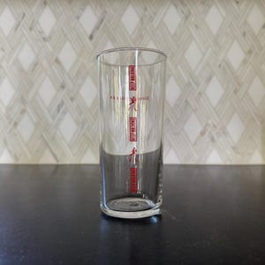 May include: A clear glass tumbler with the words "Johnnie Walker Keep Walking" printed on the side in red.