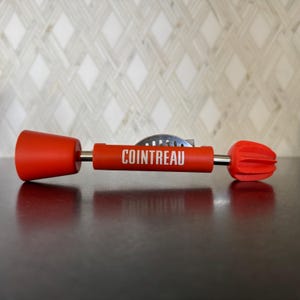 May include: A red Cointreau citrus reamer with a metal zester and a red plastic handle.