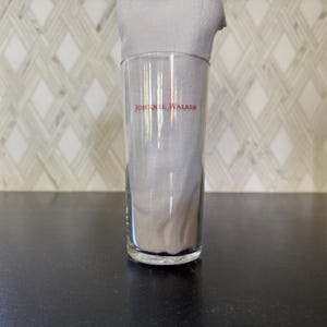 May include: A clear glass tumbler with the words "Johnnie Walker" printed in red on the side.