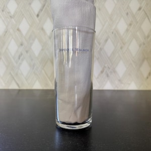 May include: A clear glass tumbler with the words "JOHNNIE WALKER" printed on the side.