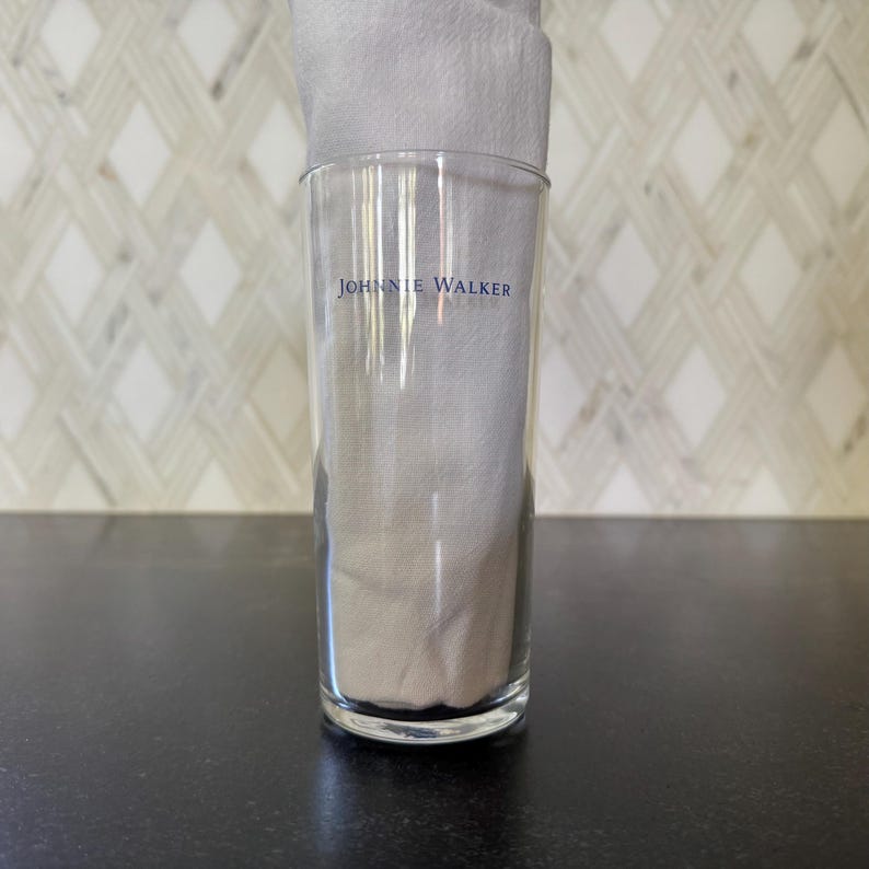 May include: A clear glass tumbler with the words "JOHNNIE WALKER" printed on the side.
