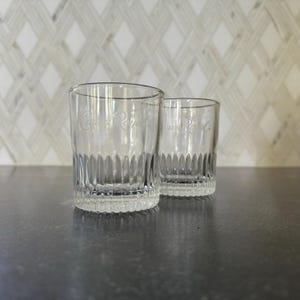 May include: Two clear glass tumblers with a ribbed design. The tumblers are etched with the words "Crown Royal".