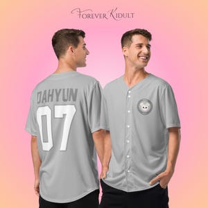 May include: Two gray baseball jerseys. One jersey has the name "DAHYUN" and the number "07" on the back. The other jersey has a circular patch with a bear illustration. The text "FOREVER KIDULT" is at the top.