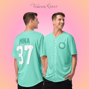 May include: A light teal baseball jersey with the name "MINA" and the number "37" on the back. The front features a circular logo with text. The jersey has a button-up front and short sleeves. The text "FOREVER KIDULT" is at the top.