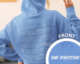 May include: A light blue hoodie with a white print of the band One Direction's song titles. The back of the hoodie has the text "One Band. One Dream. One Direction." and the names of the band members. The front of the hoodie has the text "One Direction Est. 2010".