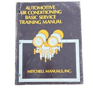 May include: A vintage automotive air conditioning basic service training manual. The cover is dark blue with yellow and white text and graphics. The manual is titled "AUTOMOTIVE AIR CONDITIONING BASIC SERVICE TRAINING MANUAL" and is published by Mitchell Manuals, Inc.