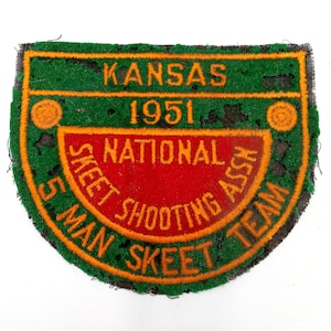 May include: A green, orange, and red embroidered patch with the text "Kansas 1951 National Skeet Shooting Assn 5 Man Skeet Team".