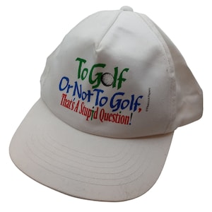 May include: White baseball cap with the text "To Golf Or Not To Golf, That's A Stupid Question!" in colourful letters. A green, white and red golf ball is depicted in the text.