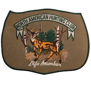 Könnte beinhalten: Brauner Aufnäher mit grünem Rand und einer Hirschillustration. Der Text "NORTH AMERICAN HUNTING CLUB" ist oben in einem Bogen angeordnet, darunter "Life Member".