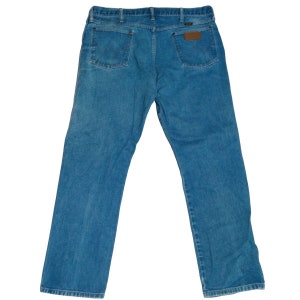 Puede incluir: Un par de pantalones vaqueros azules de mezclilla con un parche de cuero marr&oacute;n en el bolsillo trasero.