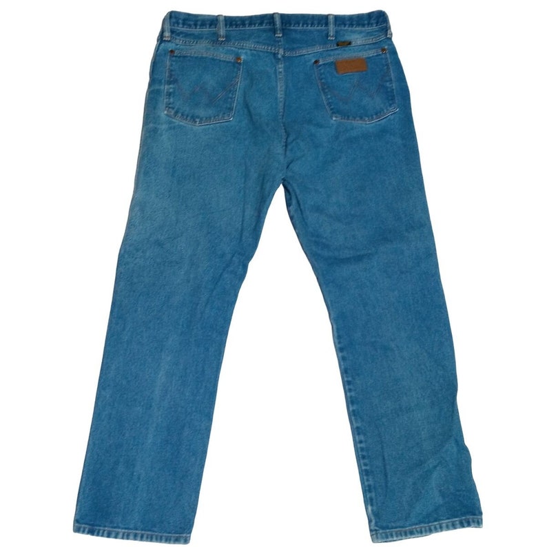 Puede incluir: Un par de pantalones vaqueros azules de mezclilla con un parche de cuero marr&oacute;n en el bolsillo trasero.