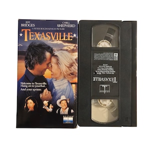May include: A VHS tape and its case for the movie "Texasville." The case features a movie poster with Jeff Bridges and Cybill Shepherd. The tape is black with the movie title printed on it.