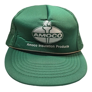 Puede incluir: Gorra de camionero verde con el logotipo de Amoco en blanco y el texto "Amoco Insulation Products". La gorra tiene una parte trasera de malla y una visera curva. Un ribete de cuerda dorada adorna la visera.