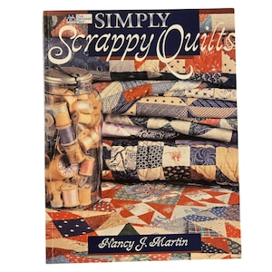 May include: A book titled "Simply Scrappy Quilts" by Nancy J. Martin. The cover features a stack of colorful patchwork quilts and a glass jar filled with spools of thread.