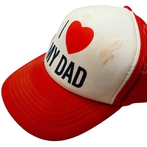 May include: A red and white trucker hat with a red heart and the text "I love my dad" in black lettering.