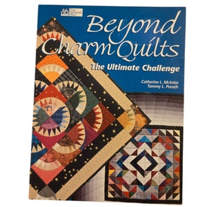 May include: Book cover with the title "Beyond Charm Quilts: The Ultimate Challenge" by Catherine L. McIntee and Tammy L. Porath. The cover features two colorful quilt designs.