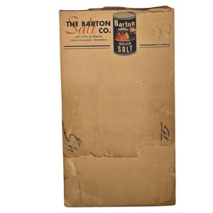 May include: Vintage Barton Salt Co. packaging. The packaging is a light brown color with the company name and logo at the top. A small can of iodized salt is featured on the packaging. The text "HUTCHINSON, KANSAS" is also visible.