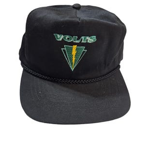 May include: Black baseball cap with a black rope detail around the brim. The front of the cap features a green and yellow embroidered logo with the word "VOLTS" above a lightning bolt inside a triangle.