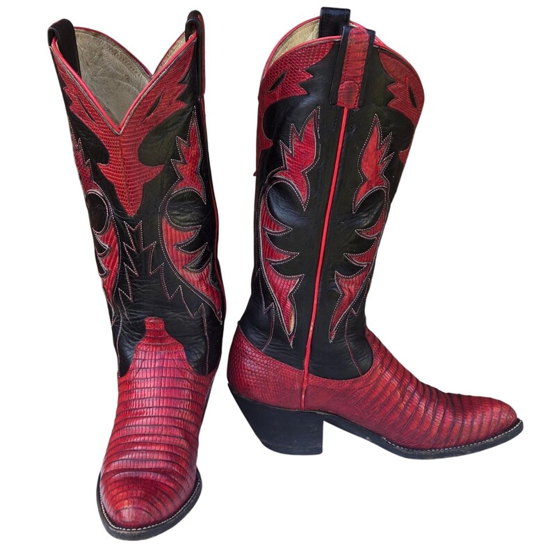 May include: Cowboy boots in red and black. The boots have a textured red foot and a black shaft with red decorative stitching. The boots have a pointed toe and a stacked heel, showcasing a classic Western style. The boots are approximately 30 cm high.
