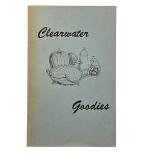 May include: A light blue booklet with the words "Clearwater Goodies" in black script. The cover features a black and white illustration of a pumpkin, pie, and other food items.