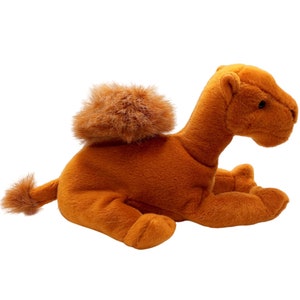 May include: A plush camel toy with a brown fur coat and a fluffy hump. The camel is lying on its belly with its head turned to the side.