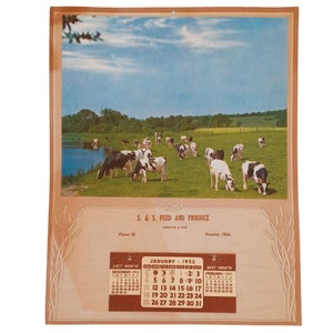 May include: A vintage calendar from January 1953 for S. & S. Feed and Produce in Hominy, Oklahoma. The calendar features a photo of a field with black and white cows grazing in a green pasture.