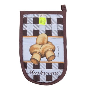 Peut inclure: Manique de four marron et blanche avec un motif de champignons. Le motif comprend un motif à carreaux marron et blanc sur le dessus et une bande bleu clair avec une illustration de champignons. Le mot "Mushrooms" est imprimé en bas.