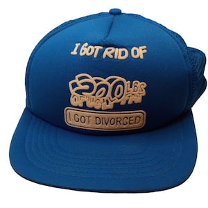 Può includere: Un cappello da camionista blu con una rete bianca sul retro. La parte anteriore del cappello ha il testo "I got rid of 200 lbs of ugly fat I got divorced" in bianco.