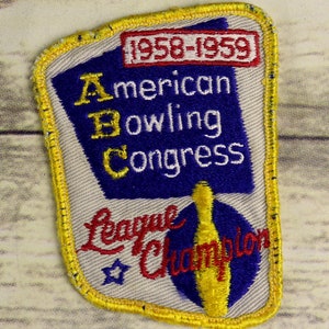 Puede incluir: Un parche bordado vintage con un pin de bolos azul y amarillo y el texto "American Bowling Congress League Champion" y "1958-1959".