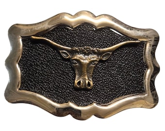 May include: A silver belt buckle with a brown leather background and a gold longhorn steer head design.