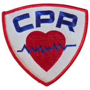 May include: A white, triangular patch with a red heart and a blue EKG line. The text "CPR" is embroidered in blue above the heart.