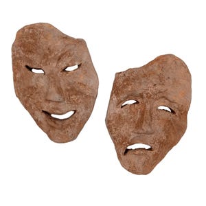 May include: Two hand-sculpted clay masks with a rough, textured brown finish. One mask features a smiling expression with almond-shaped eyes and a curved mouth, while the other displays a somber, downturned expression with a furrowed brow.