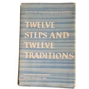 Könnte beinhalten: Ein Buch mit dem Titel "Twelve Steps and Twelve Traditions" von Alcoholics Anonymous. Das Cover ist hellblau mit horizontalen Streifen und weißem Text. Der Text oben lautet: "Ein Mitbegründer der Anonymen Alkoholiker erzählt, wie sich Mitglieder erholen und wie die Gesellschaft funktioniert."