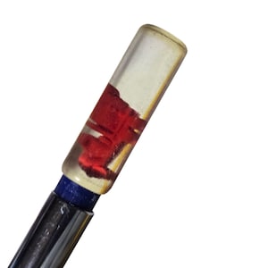 Op de afbeelding: Een heldere, rechthoekige flesstopper met een rood, abstract ontwerp aan de binnenkant. De stopper heeft een blauwe band en een zilveren metalen steel. Het ontwerp is zichtbaar door het heldere glas.