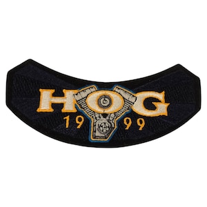 May include: A navy blue, curved patch with the letters "HOG" in gold, and a detailed engine graphic. The numbers "19" and "99" are below the letters. The patch is likely for a motorcycle club.