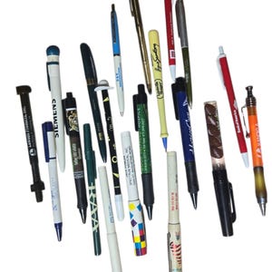 Könnte beinhalten: Eine Sammlung verschiedener Stifte, darunter Kugelschreiber und Stifte, in einer Vielzahl von Farben und Designs. Einige Stifte zeigen Firmenlogos und Texte wie "Lawson Products, Inc." und "Siemens."