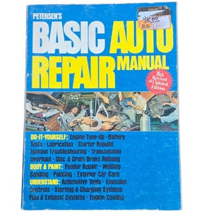 May include: A vintage "Petersen's Basic Auto Repair Manual" book. The cover is blue with yellow text, featuring the title and a graphic of mechanics working on cars. The book covers various repair topics, including engine tune-up, body and paint, and more.