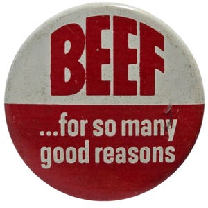 Puede incluir: Un botón redondo con la mitad superior blanca y la inferior roja. La palabra "BEEF" está en letras rojas grandes en la sección blanca. Debajo, en la sección roja, el texto blanco: "...for so many good reasons".