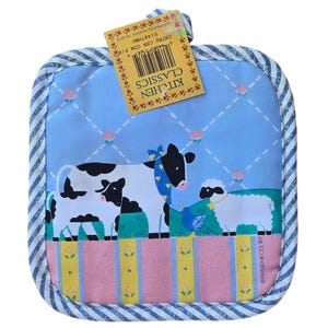May include: Square Kitchen Classics pot holder with a blue and white striped border. The center features a farm scene with cows, a sheep, and a bird on a light blue background with a pink and yellow striped bottom. A Kitchen Classics tag is attached.