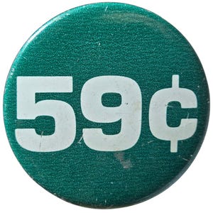 May include: A round, teal button with the white text "59¢" in a bold, sans-serif font. The button has a textured surface and a slight sheen. The design is simple and eye-catching.