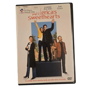 May include: DVD cover for the movie "America's Sweethearts" starring Catherine Zeta-Jones and John Cusack. The cover features a photo of the actors in a scene from the movie. The text "A comedy about celebrity, family and other forms of insanity" is printed at the bottom of the cover.