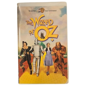 May include: A VHS tape of "The Wizard of Oz" featuring the film's title in yellow and the characters Dorothy, Scarecrow, Tin Man, and Cowardly Lion. The Warner Bros. and WB Family Entertainment logos are at the top.