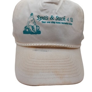 Puede incluir: Gorra de camionero blanca con un logotipo verde que dice "Spas & Such 4 U" y "Your one stop home recreation shop."