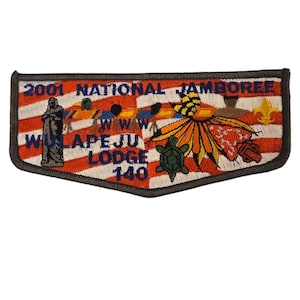 Könnte beinhalten: Ein grauer und blauer gestickter Aufnäher mit dem Text "2001 National Jamboree" und "Wilape-Ju Lodge 140". Der Aufnäher zeigt ein rot-weiß-blaues amerikanisches Flaggenmuster mit einem indianischen Kopfschmuck, einer Schildkröte und anderen Symbolen.