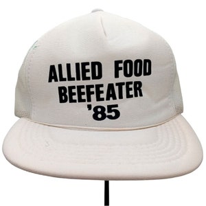 May include: White trucker hat with black text that reads "Allied Food Beefeater '85".
