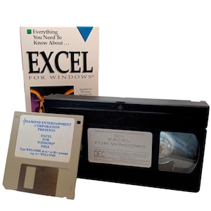 May include: A VHS tape and a floppy disk with the text "Diamond Entertainment Corporation Presents Excel for Windows 95014" on both. The VHS tape has a black case with a silver label and the text "Diamond Entertainment Corporation 95014 Excel for Windows" on it. The floppy disk is beige with a black label and the text "Diamond Entertainment Corporation Presents Excel for Windows 95014" on it. The floppy disk has a small, black, rectangular opening in the center.