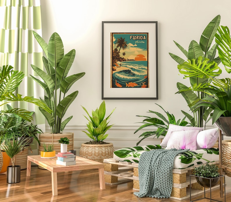 May include: A living room interior with a couch featuring a tropical leaf print and a throw blanket. The couch is in front of a white wall with a framed vintage poster that reads "FLORIDA" with a palm tree and ocean scene. The room is decorated with potted plants, including a large banana plant, a smaller plant in a woven basket, and a small potted plant on a wooden coffee table.
