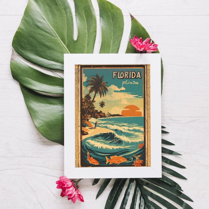 May include: A white framed print with a vintage style illustration of a beach scene in Florida. The print features a palm tree, ocean waves, and the text "Florida" in a retro font.