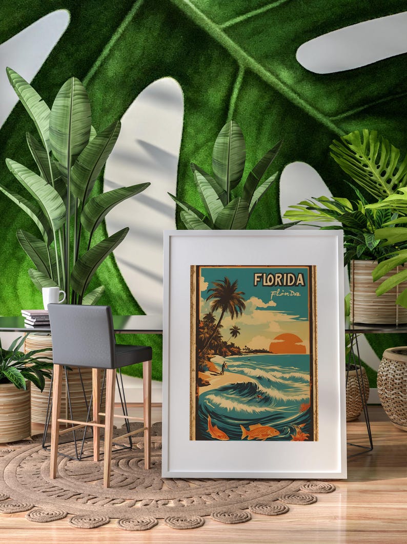 May include: A white framed poster with a vintage style illustration of a beach scene in Florida. The poster has the text "FLORIDA" in bold letters and "Fl'nda" in smaller letters below it.