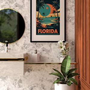 Peut inclure: Une affiche encadr&eacute;e avec une illustration r&eacute;tro d'une sc&egrave;ne de plage en Floride. L'affiche repr&eacute;sente des palmiers, un coucher de soleil bleu et orange, et le mot "FLORIDA" en lettres orange et audacieuses.